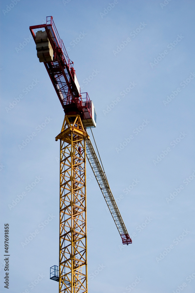 Large construction site crane working on a building complex with clear blue sky. Large construction site crane working on a building complex with clear blue sky.