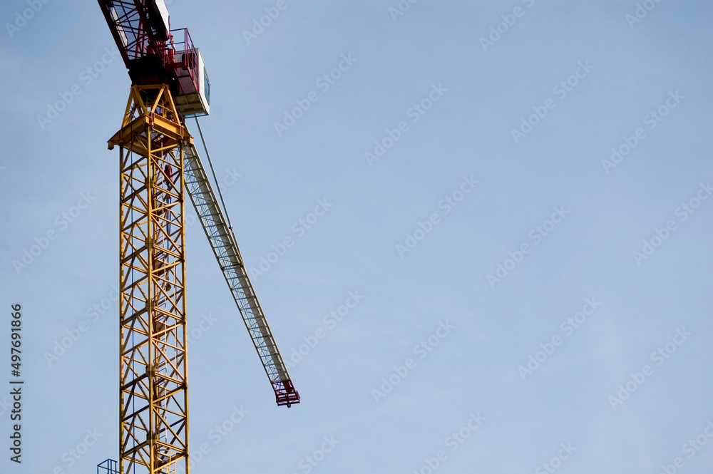 Large construction site crane working on a building complex with clear blue sky.