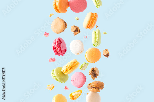 Colorful macarons biscuits float in the air on a pastel blue background. Summer colors sweet food cookies aesthetic concept. Trendy wallpaper.