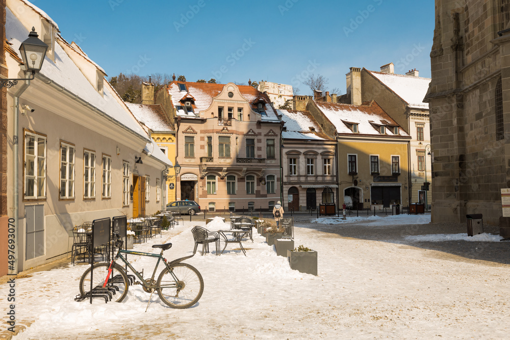 BRASOV, ROMANIA - March 2022: Street and old houses in Brasov old town on winter day, Romania