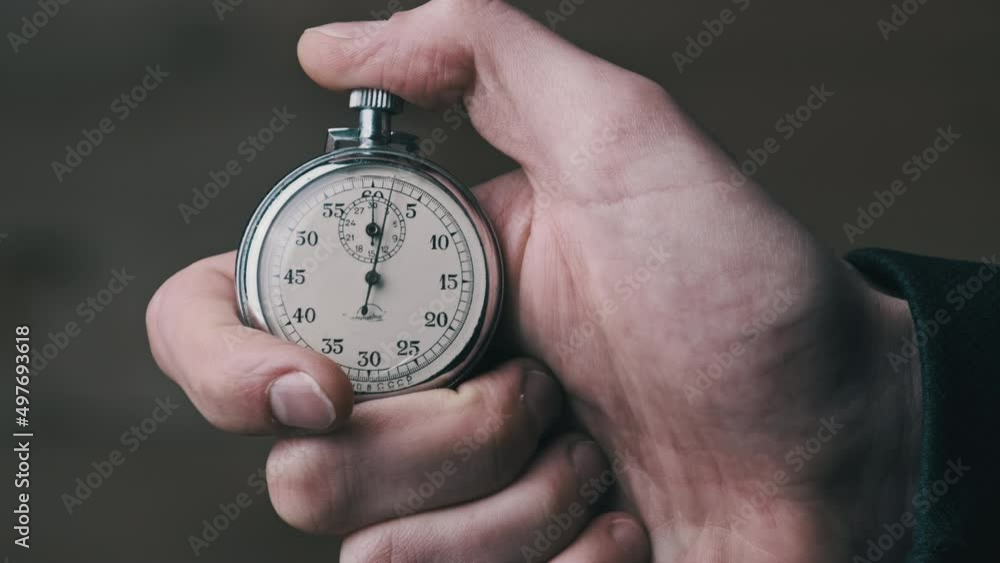 Stopwatch in hand. Analogue Stopwatch in Man Hand counts down seconds