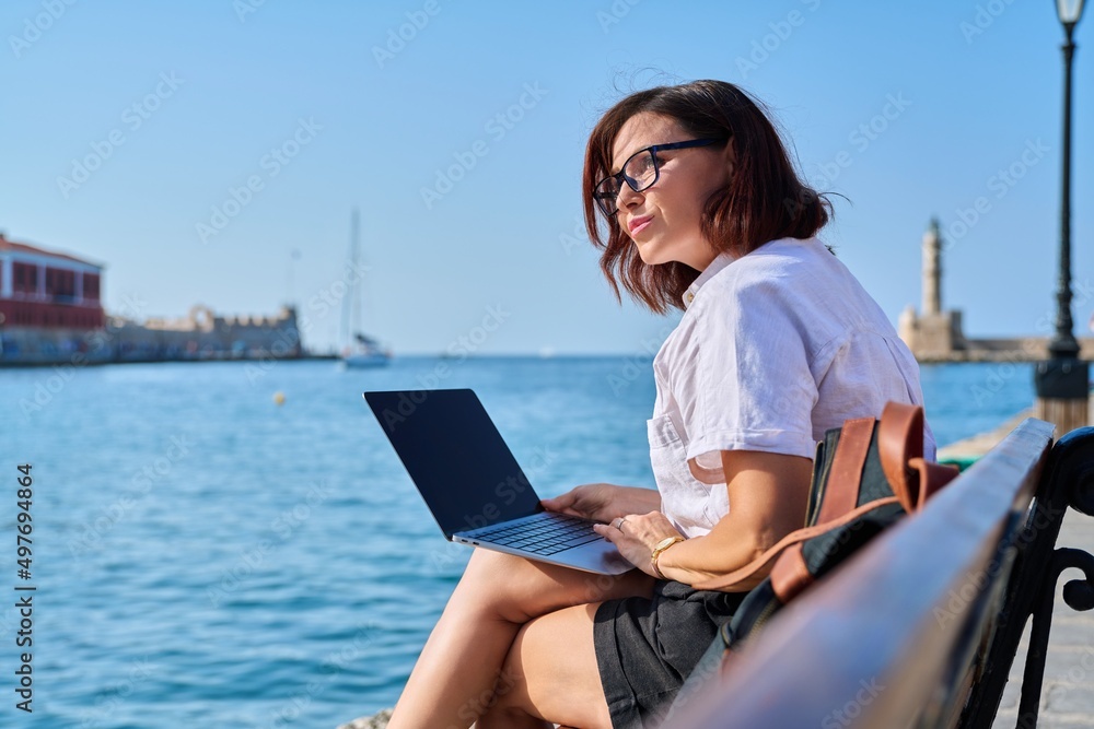 Business mature woman sitting outdoor using laptop.