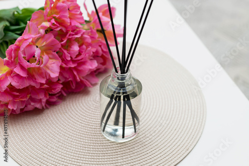 aroma reed diffuser and bouquet of beautiful tulip flowers on white table. Aromatherapy, home decor concept. blurred background