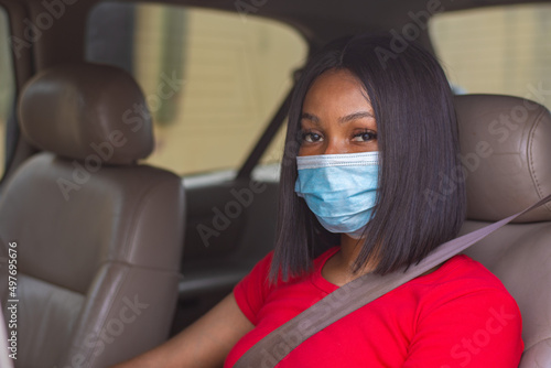 african lady with a face mask driving her car