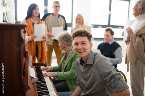Canvas Print Group of seniors with young teacher singing together at choir rehearsal