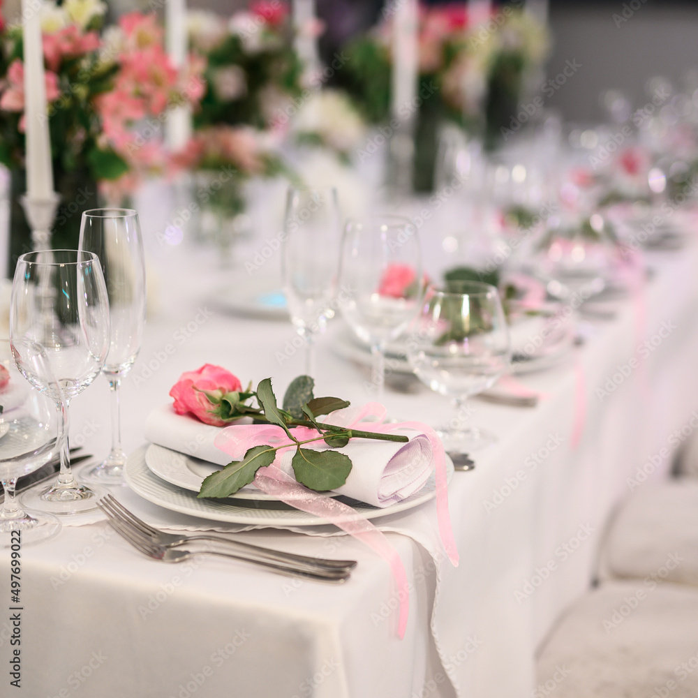 Candles and vase with white roses placed on round table near wineglasses during romantic date in garden Candles and vase with white roses placed on round table near wineglasses during romantic date in garden
