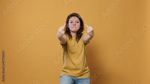 Angry woman showing middle finger obscene hand gesture having aggressive attitude problem being rude and disrespectful in studio. Unhappy person having conflict showing aggresion and anger. photo