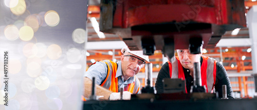 Professional Metal factory engineers are stamping steel plates with industrial printing presses.