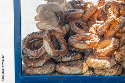 Polish street food - Polish bagels in Krakow, round pretzels with poppy seeds and cumin behind the glass of a street stall in the sunlight
