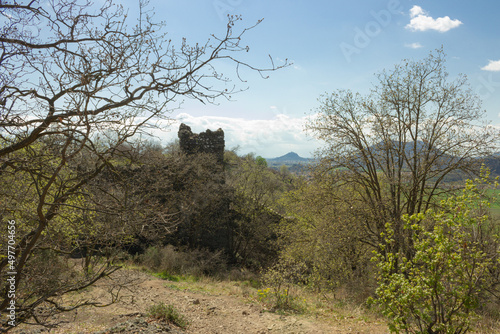 Hilly landscape. Path on Monte Ceva (Padua, Italy) in the middle of the woods and bushes with the view of the remains of an ancient tower.