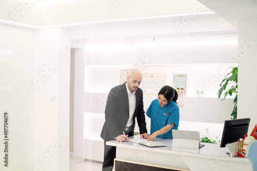 Young Assistant making  Appointment on Reception in Dental Clinic.