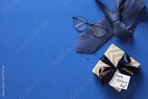 Fathers day background with gift box, necktie, glasses on blue. Happy Fathers Day greeting card design.