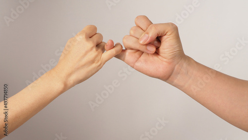 Man and woman do Pinky promise or pinky swear hands sign on white background. photo