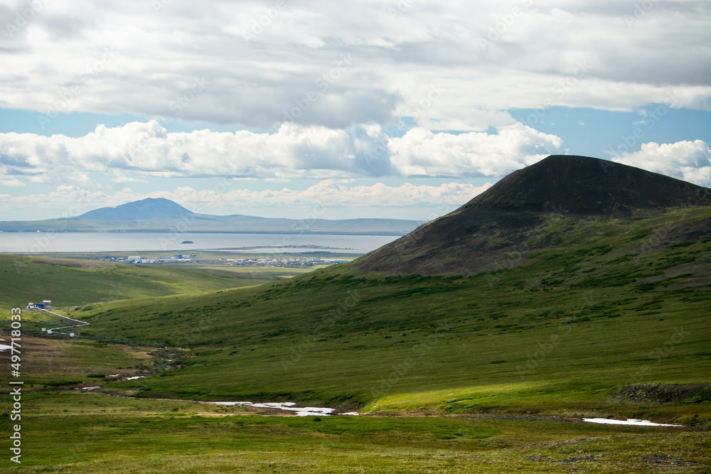 Summer Arctic landscape. View of the tundra and mountains. In the distance, the settlement of Ugolnye Kopi, Anadyr Airport and the Anadyr estuary. Chukotka, Siberia, Far East of Russia.