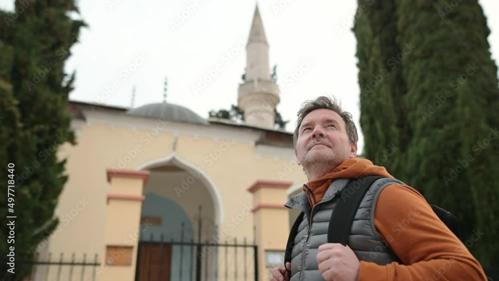 Mature tourist enjoy a stroll through the old town of Trebinje, Bosnia and Herzegovina. Backpacker examines the facade of Osman Pasha Mosque in the historical center of the Trebinye Mature tourist enjoy a stroll through the old town of Trebinje, Bosnia and Herzegovina. Backpacker examines the facade of Osman Pasha Mosque in the historical center of the Trebinye