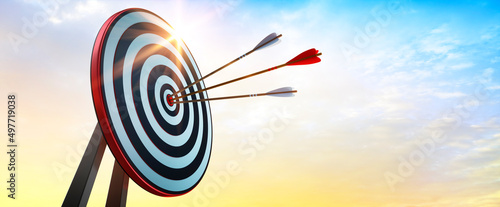 Fotografia Achieve goals - dart board with arrows in the evening sun