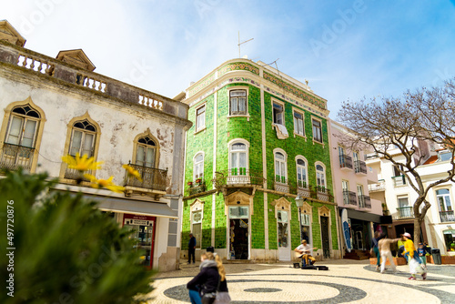 Historical town centre in Lagos, Algarve, Portugal with moving people and a green tiled building.