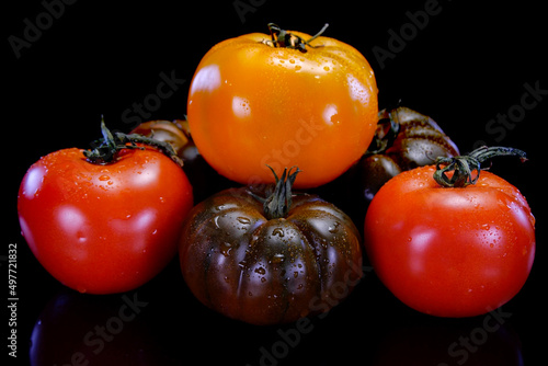 Different kinds of tomatoes on a black background. Fresh, perfect and firm tomato. Restaurant, groceries store or agriculture promo.