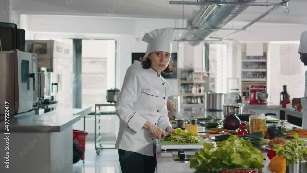 Portrait of female cook cutting green celery in gourmet kitchen, using cutting board and knife to slice coleslaw salad. Woman chef with uniform preparing ingredients for food recipe. Portrait of female cook cutting green celery in gourmet kitchen, using cutting board and knife to slice coleslaw salad. Woman chef with uniform preparing ingredients for food recipe.