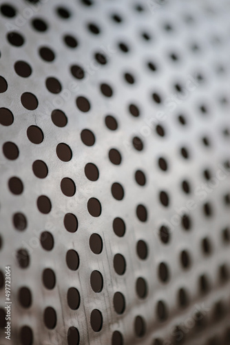 Metal fragment, chrome-plated surface with perforations in the form of round holes, metal colander. Close-up