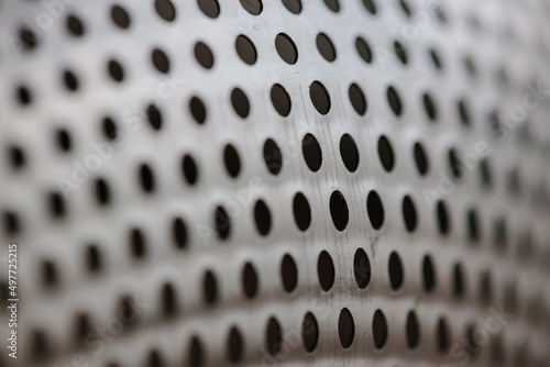 Metal fragment, chrome-plated surface with perforations in the form of round holes, metal colander. Close-up