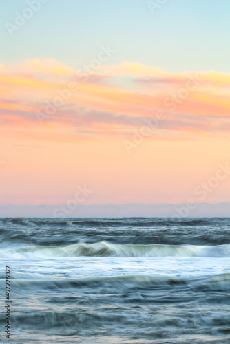 Motion blur in crashing waves under a beautifully colorful sunset sky. Long Island, New York