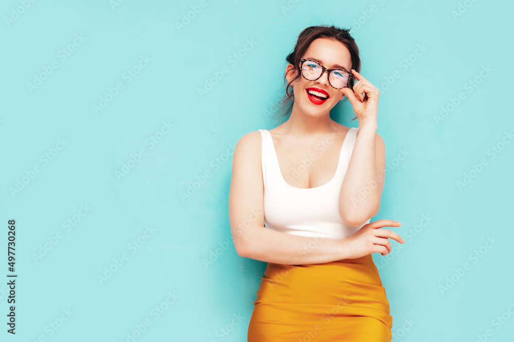 Young beautiful smiling female in trendy summer yellow skirt clothes. Sexy carefree woman posing near wall in studio. Positive model having fun. Cheerful and happy. Isolated. In spectacles Young beautiful smiling female in trendy summer yellow skirt clothes. Sexy carefree woman posing near wall in studio. Positive model having fun. Cheerful and happy. Isolated. In spectacles