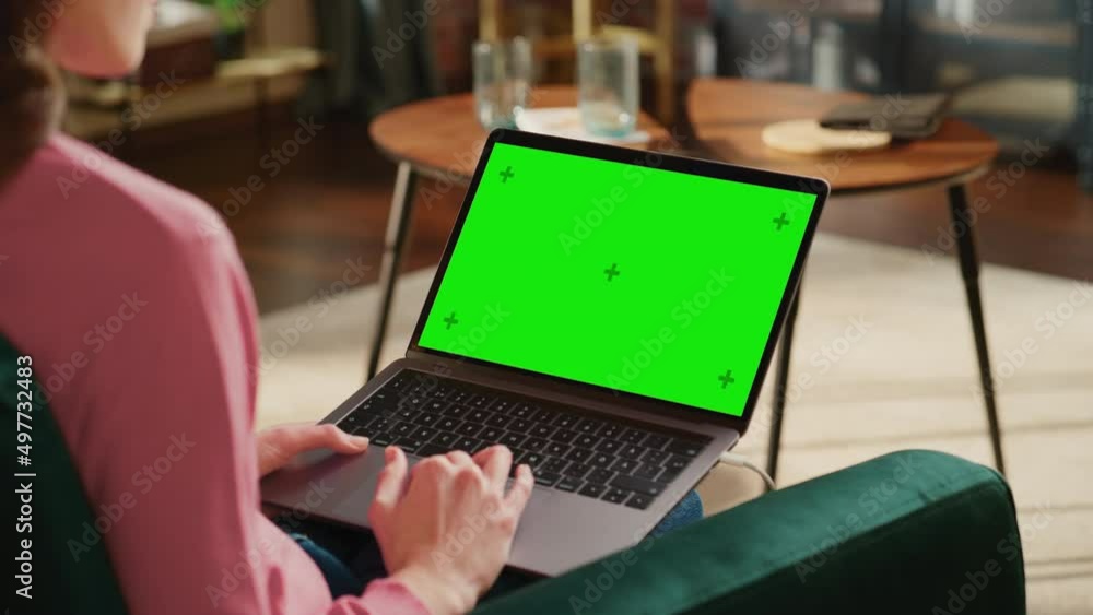 Young Adult Woman Working from Home Loft Apartment on Laptop Computer with Green Screen Mock Up Display. Creative Female Browsing the Web, Writing on Social Media. Close Up Over the Shoulder Footage. Young Adult Woman Working from Home Loft Apartment on Laptop Computer with Green Screen Mock Up Display. Creative Female Browsing the Web, Writing on Social Media. Close Up Over the Shoulder Footage.