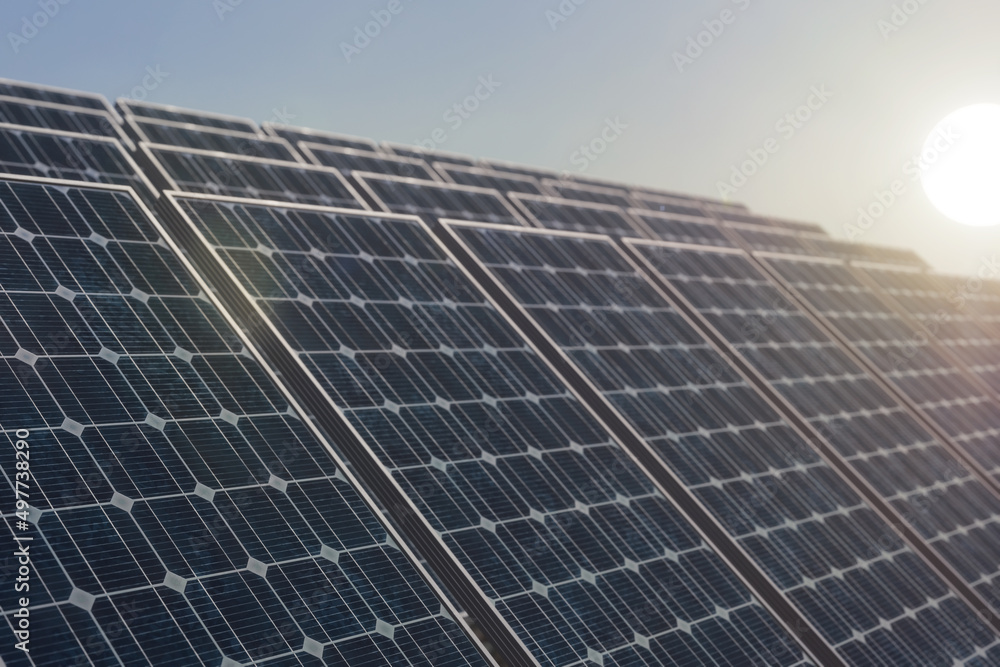 Solar power plant against the rising sun, selective focus on the first solar panel. Alternative energy concept Solar power plant against the rising sun, selective focus on the first solar panel. Alternative energy concept