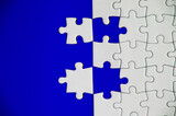 Top view of separated jigsaw puzzle on blue cover background. Copy spave