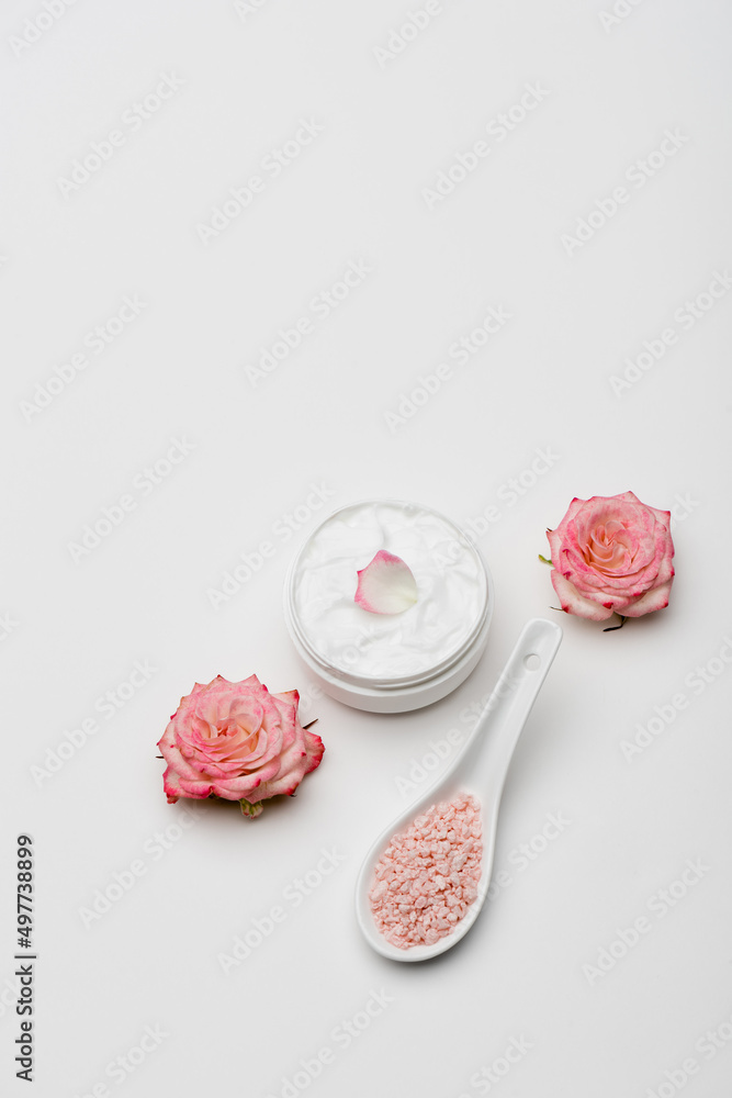 top view of flowers near pink sea salt and container with cream on white. top view of flowers near pink sea salt and container with cream on white.