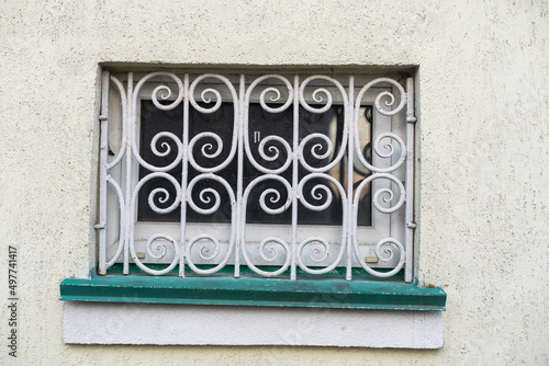 Forged lattice with pattern on closed window of an antique red brick rear.
