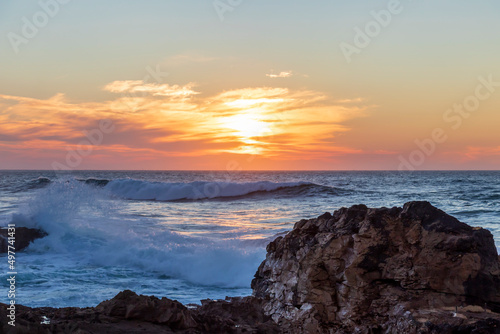 Sunset at Atlantic ocean coast with cliffs  rock formations and a dramatic sky over the white strong waves  Portugal