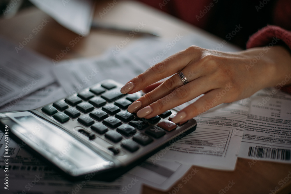 Close-up female hands with a calculator and abacus in the living room at home. A young woman calculates monthly household expenses Close-up female hands with a calculator and abacus in the living room at home. A young woman calculates monthly household expenses