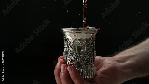 Super slow motion Phantom high-speed camera of wine pouring into silver Sabbath cup. Jews all around the world say the traditional blessing for Shabbat over kosher wine, celebrating the day of rest. photo
