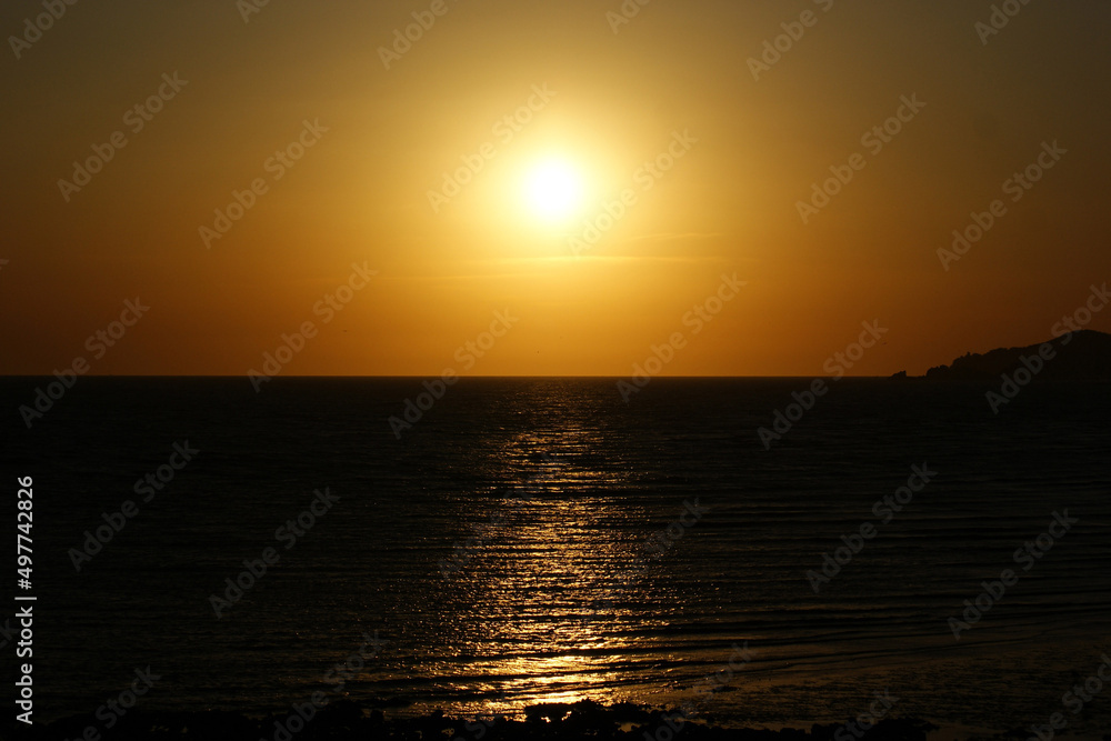 The golden sunset is reflected in the sea.
