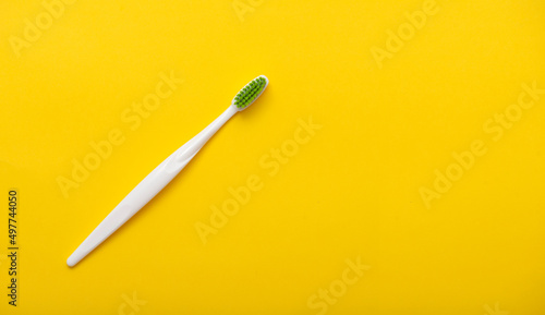 White plastic toothbrush on bright yellow background as flat lay, top view, space for text