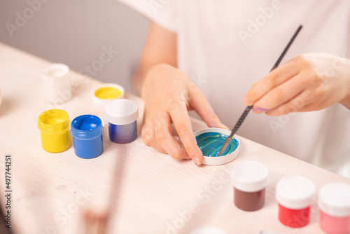 boy in a white t-shirt paints eggs to celebrate the Easter holiday with bright colors. Childish art  handmade culture concept. Boy with a brush in his hand paints an egg.