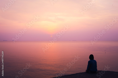 Woman on holiday, looking to sea with beautiful view in the evening. Sunset at the island, romantic background concept.