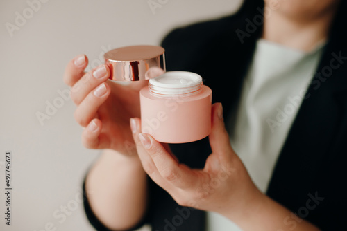 woman holds in her hands a pink jar of moisturizer white. cosmetic cream. skin care. dermatology. body and face cream.