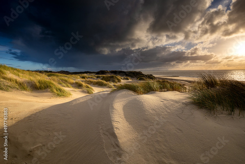 sunset over sand dunes at sea