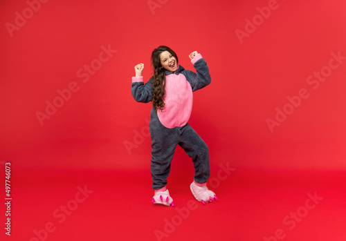 happy successful teen girl in soft night suit standing on red background, pajamas