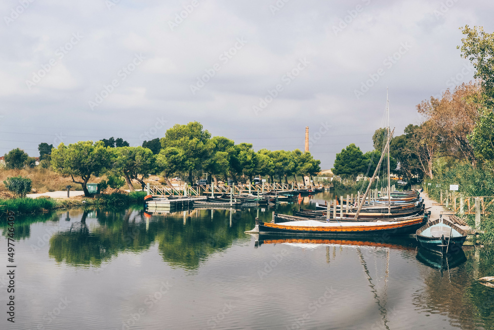 Traditional fisherman river port with manual sailboats and diverse nature behind 