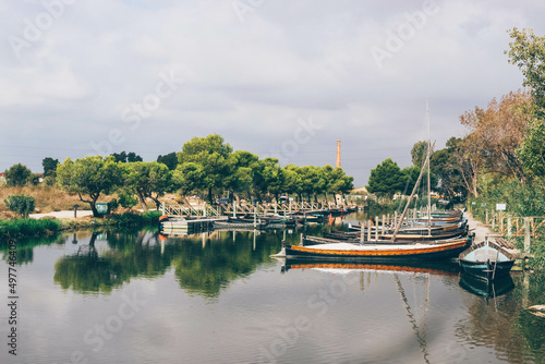 Traditional fisherman river port with manual sailboats and diverse nature behind 