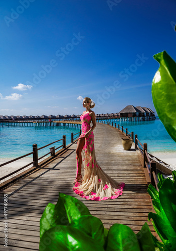 Luxury fashion. Elegant fashion model is posing outdoor. Stylish female model in long gown dress on the Maldives beach. Elegance. Classy woman in amazing dress on Maldives landscape. Couture. Vogue.