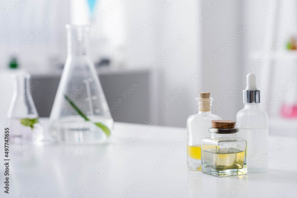bottle with essential oils near serum and flasks in lab. bottle with essential oils near serum and flasks in lab.