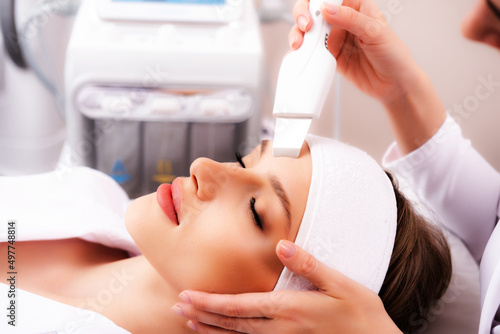 Photo of a beautiful woman's face during a facial cleaning procedure with an ultrasonic machine in a cosmetology clinic. The concept of cosmetology and skin care.