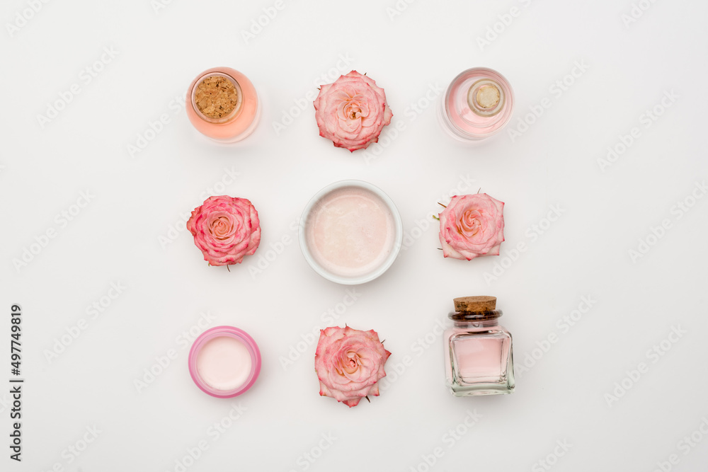 top view of flowers near cream and bottles with cosmetic products on white. top view of flowers near cream and bottles with cosmetic products on white.