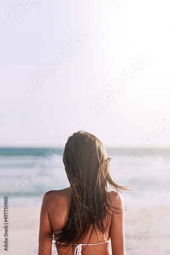 The beach will always be the perfect summer destination. Rearview shot of an unrecognizable young woman at the beach.