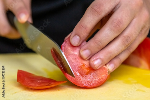 The cook separates the pulp from the skin of tomatoes on a yellow board